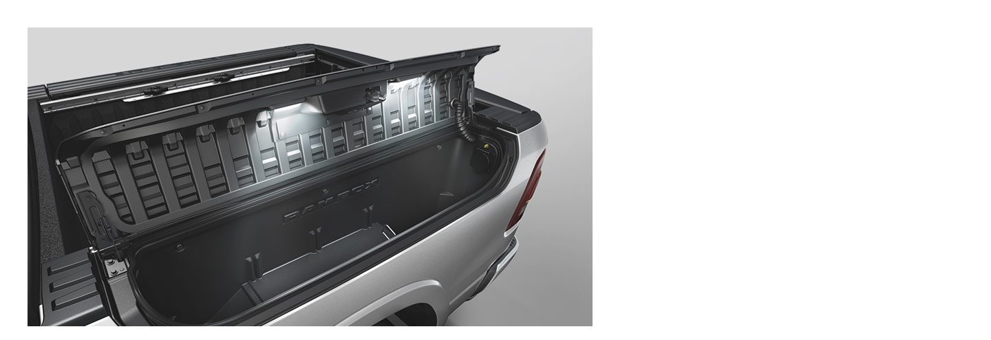 The available RamBox Cargo Management System on 2020 Ram 1500 with the lid raised and interior lights on.