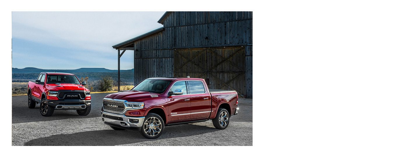 A three-quarter side view of two 2020 Ram 1500 models parked side by side on the beach.