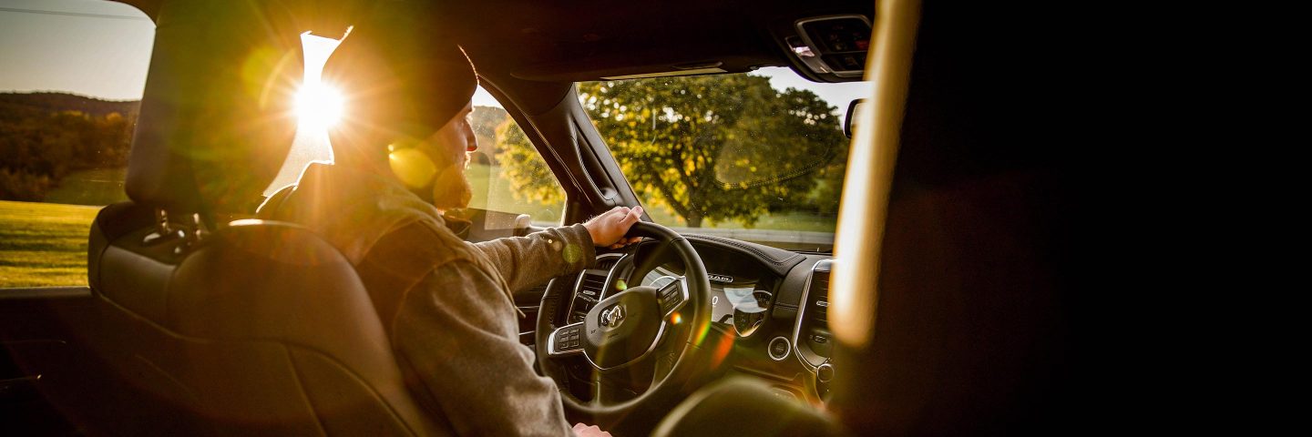 A driver at the wheel of the 2022 Ram 2500 with the sun beaming through the windows.