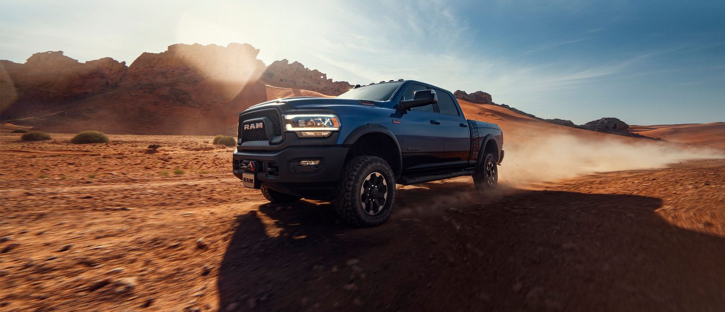 The 2022 Ram 2500 towing a flatbed trailer with an excavator on it.