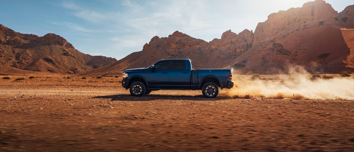 The 2022 Ram 2500 towing a flatbed with a tractor on it.