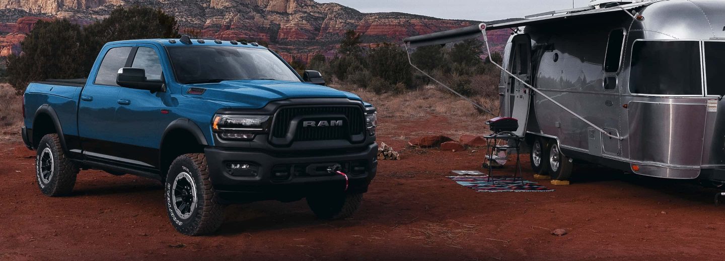 The 2022 Ram 2500 parked in the desert beside a camper.