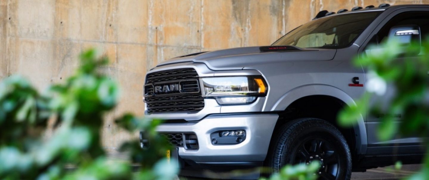 A black 2022 Ram 1500 Rebel and a red 2022 Ram 1500 Laramie at the starting line of a racetrack. The Ram Truck Month logo.