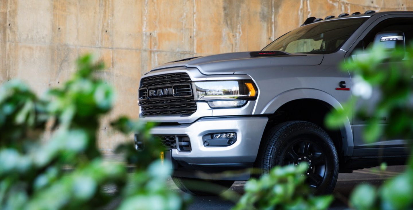 A black 2022 Ram 1500 Rebel and a red 2022 Ram 1500 Laramie at the starting line of a racetrack. The Ram Truck Month logo.