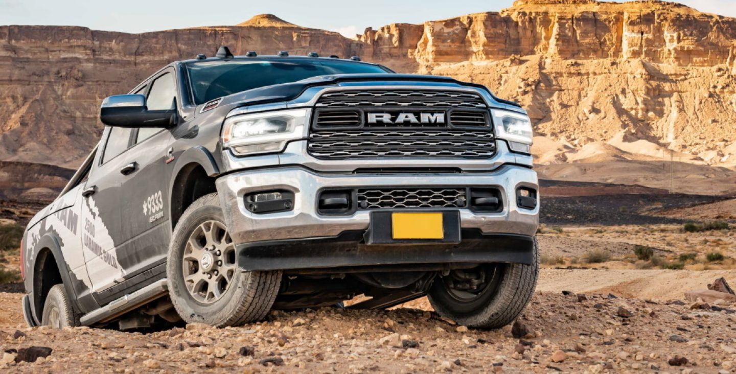 A red 2022 Ram 2500 Limited 4x4 Crew Cab with its headlamps on, parked in a commercial garage. The Ram Truck Month logo.
