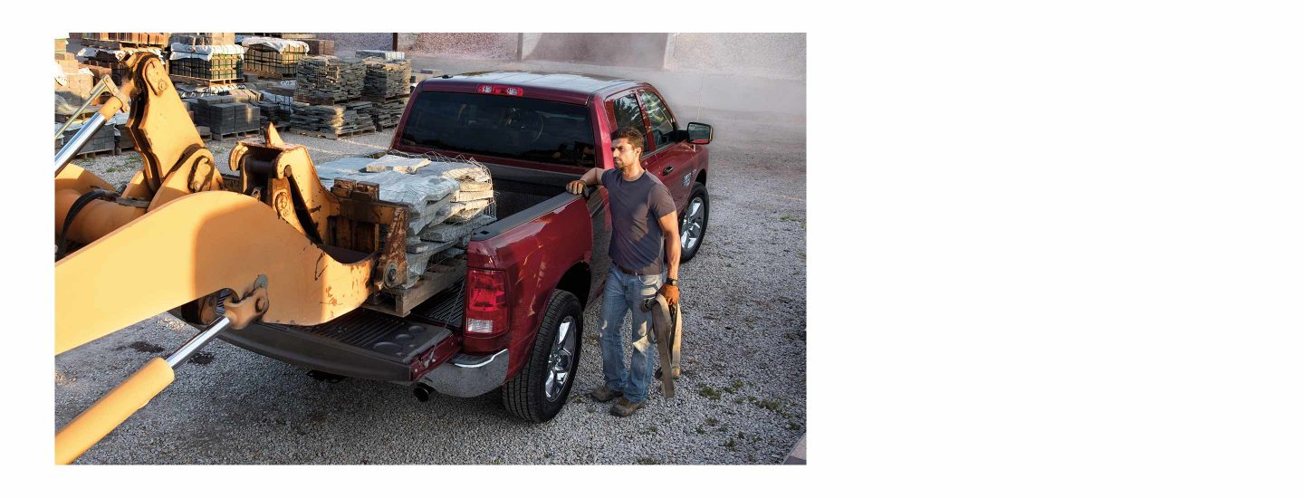 A forklift loading a pallet of paving stones into the bed of a 2022 Ram 1500 Classic.