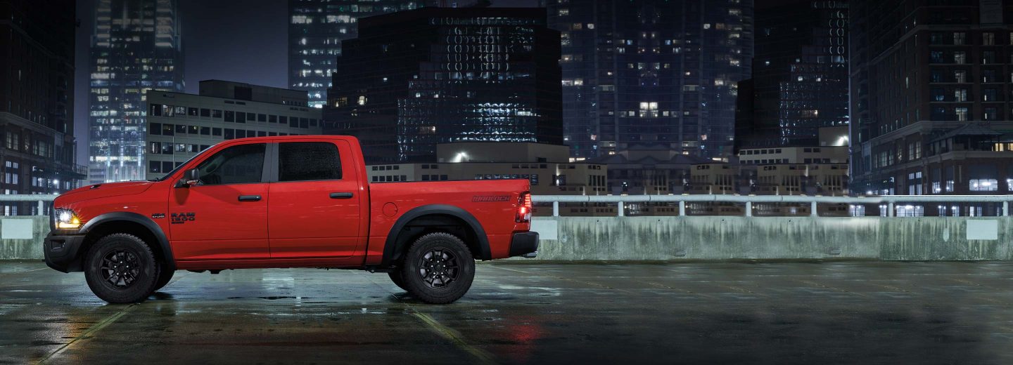 A 2023 Ram 1500 Classic Warlock 4x4 parked on the roof of a parking garage with skyscrapers in the background.