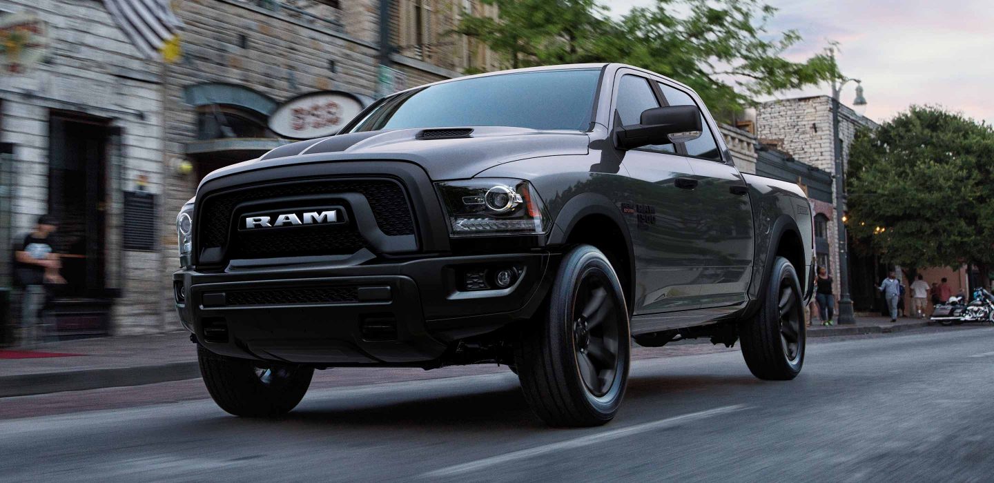 The 2022 Ram 1500 Classic parked at the curb outside a brick building.