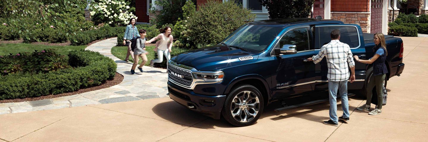 A family of five approaching a 2022 Ram 1500 parked outside a house.