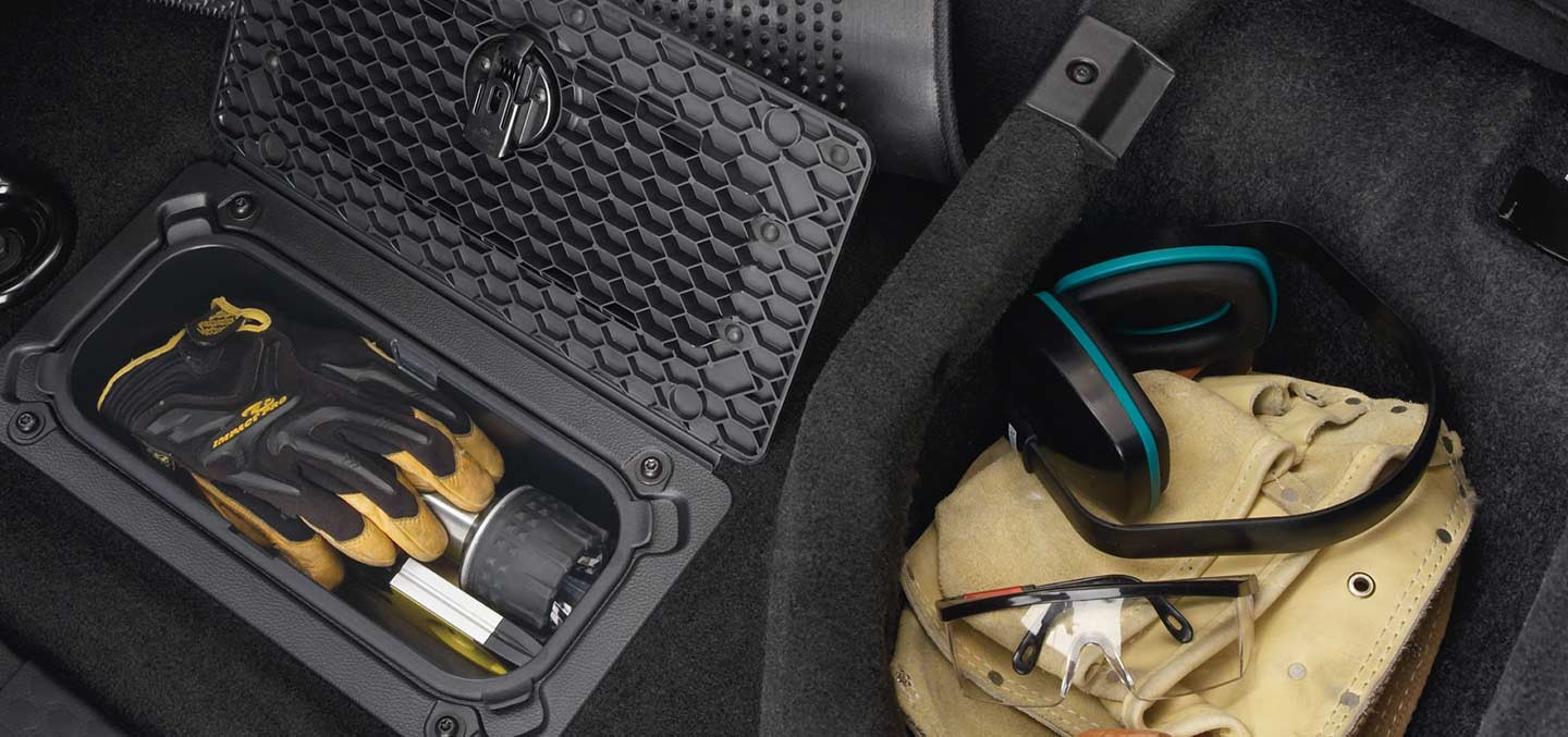 A close-up of the under-seat storage compartment and the in-floor RamBin in the 2023 Ram 1500 Classic with gloves and tools inside.