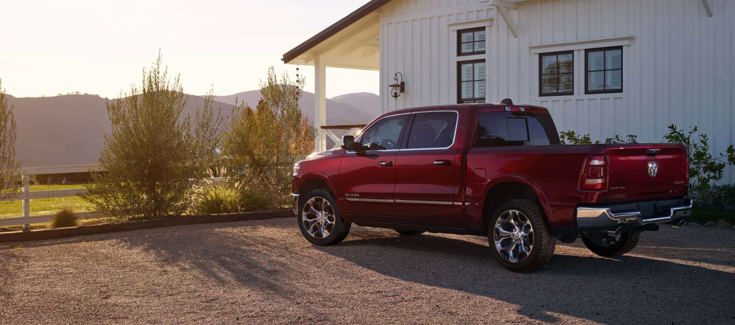 The 2023 Ram 1500 parked on a gravel driveway beside a farmhouse.