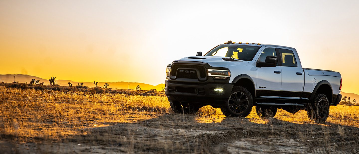 Una Ram 2500 Rebel 2023 estacionada en un claro cubierto de hierbas al amanecer.