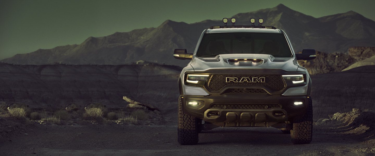 A head-on view of the 2023 Ram 1500 TRX parked off-road at the foot of a hill range.