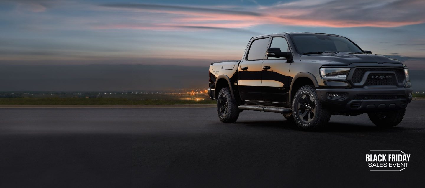 Böyük bir evin avtomobil yolunda park edilmiş mavi 2024 Ram 1500 Limited Crew Cab-in ön bucaqlı sərnişin tərəfi profili. Enerji Günlərinin Satış Tədbiri.