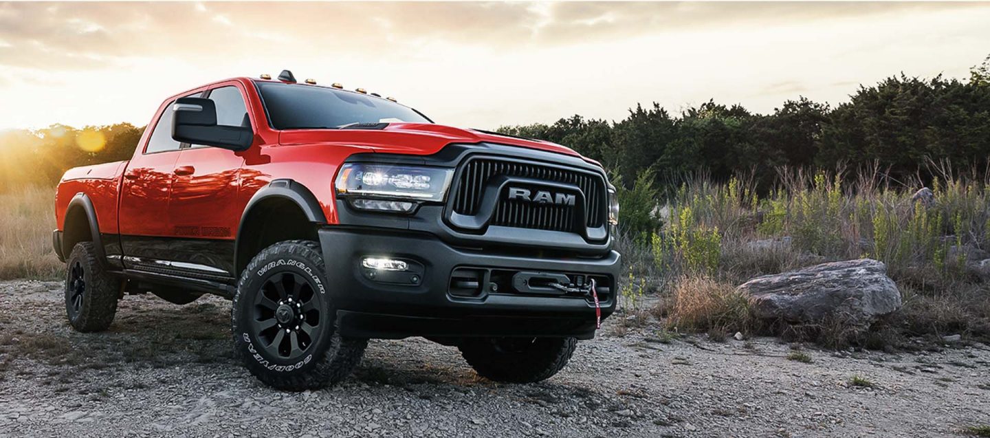 Perfil frontal angular del lado del pasajero de una Ram 2500 Power Wagon 2024 roja estacionada en un sendero de tierra.