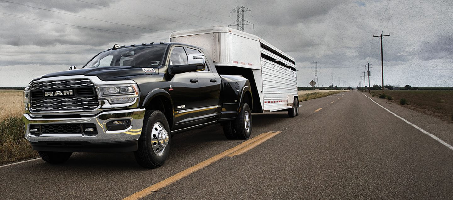 Una Ram 3500 Limited Crew Cab 2024 negra llevando un tráiler de viaje de quinta rueda por una carretera.