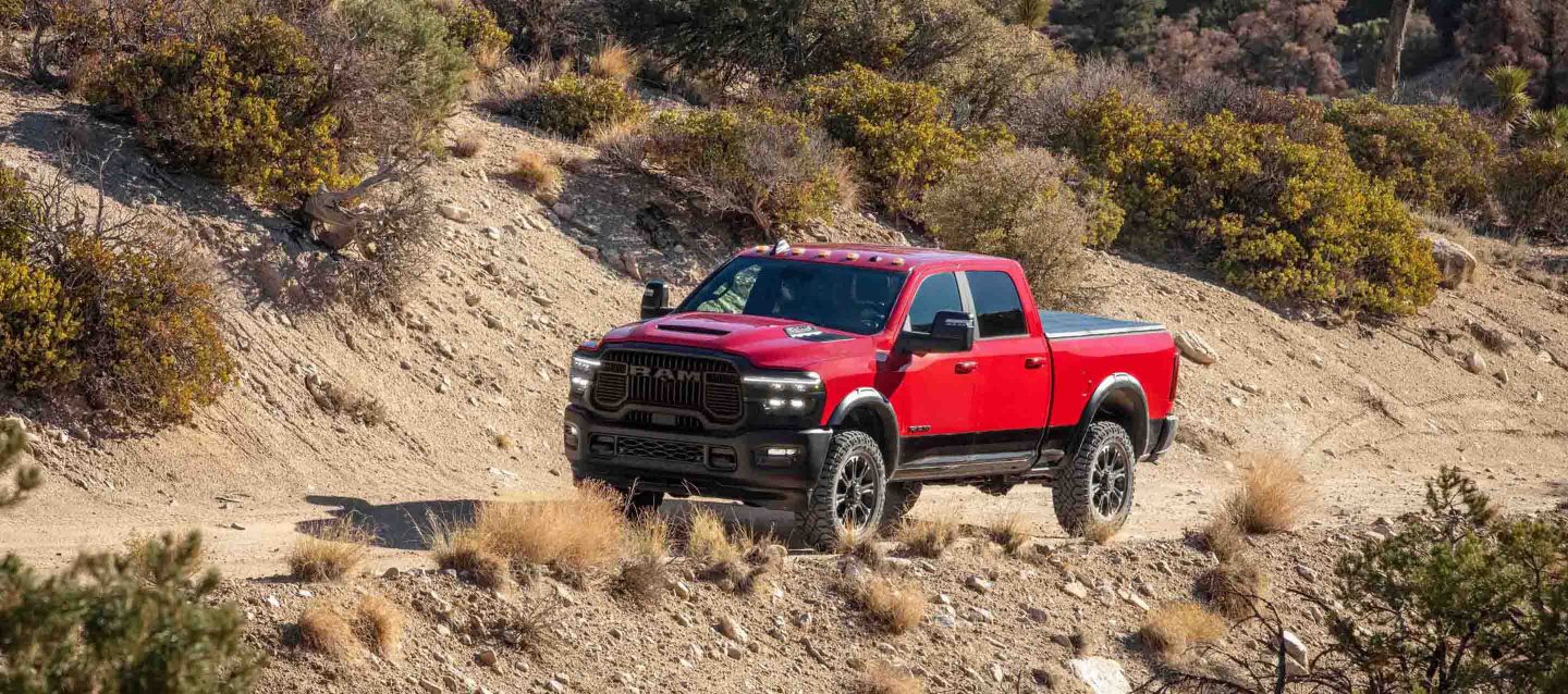 Una Ram 2500 Laramie 4x4 Crew Cab 2025 roja circulando por una carretera todoterreno.