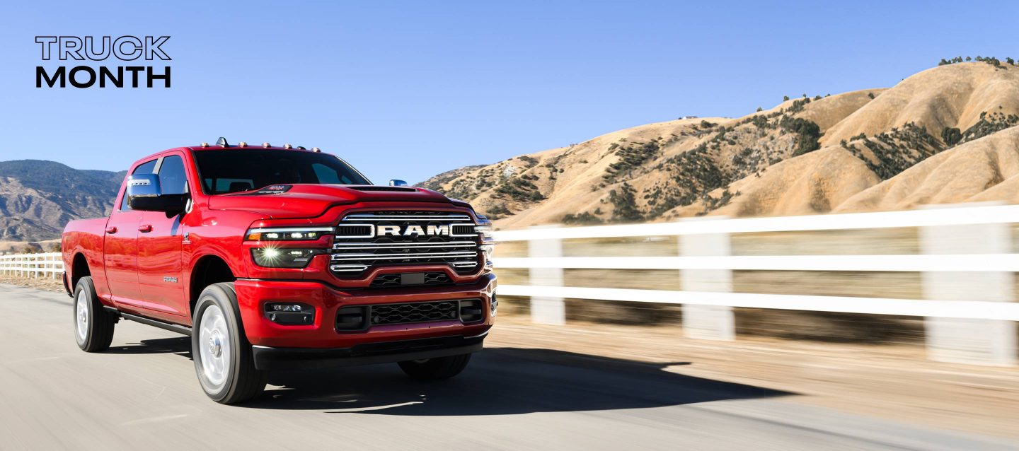 Una Ram 2500 Laramie 4x4 Crew Cab 2025 roja circulando por una carretera, con montañas de fondo.