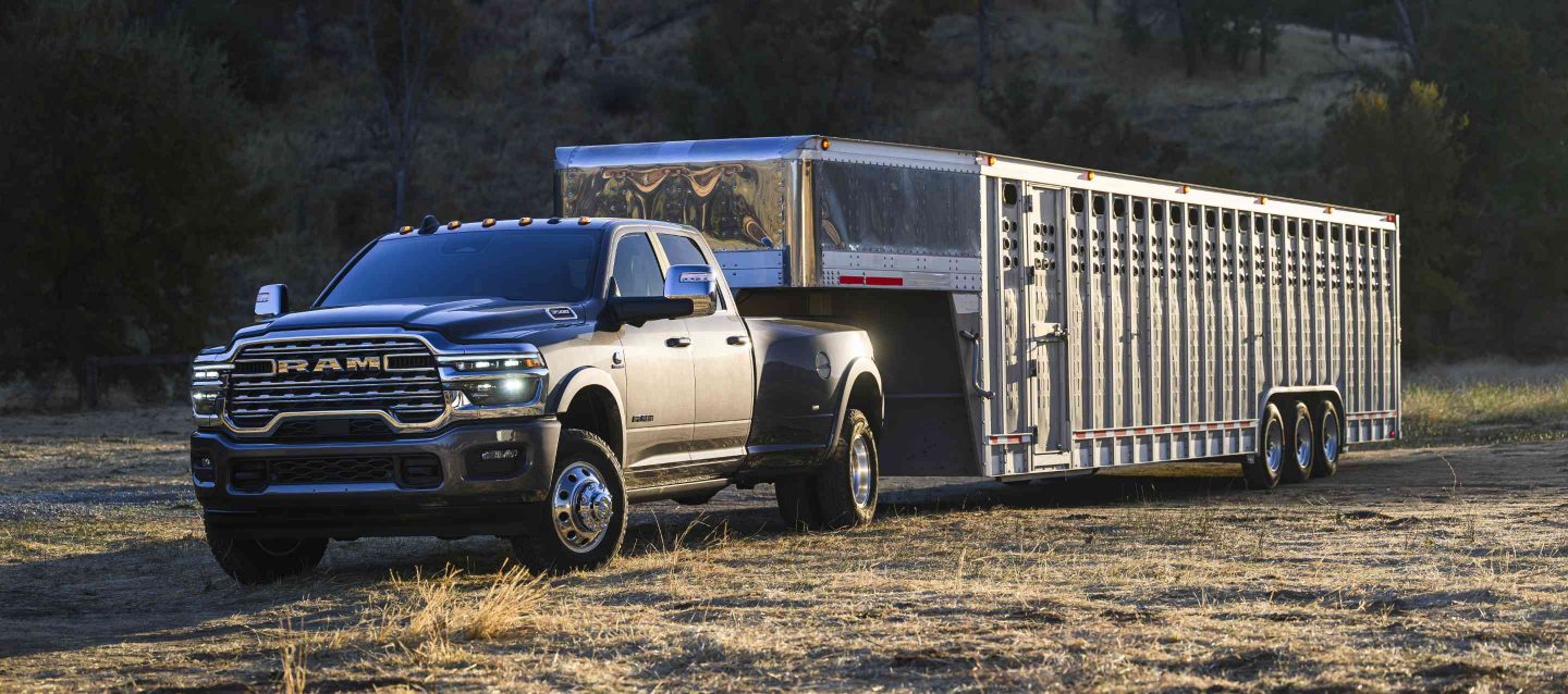 Una Ram 3500 Limited Longhorn 4x4 Crew Cab 2025 gris acarreando un remolque de quinta rueda grande para ganado.