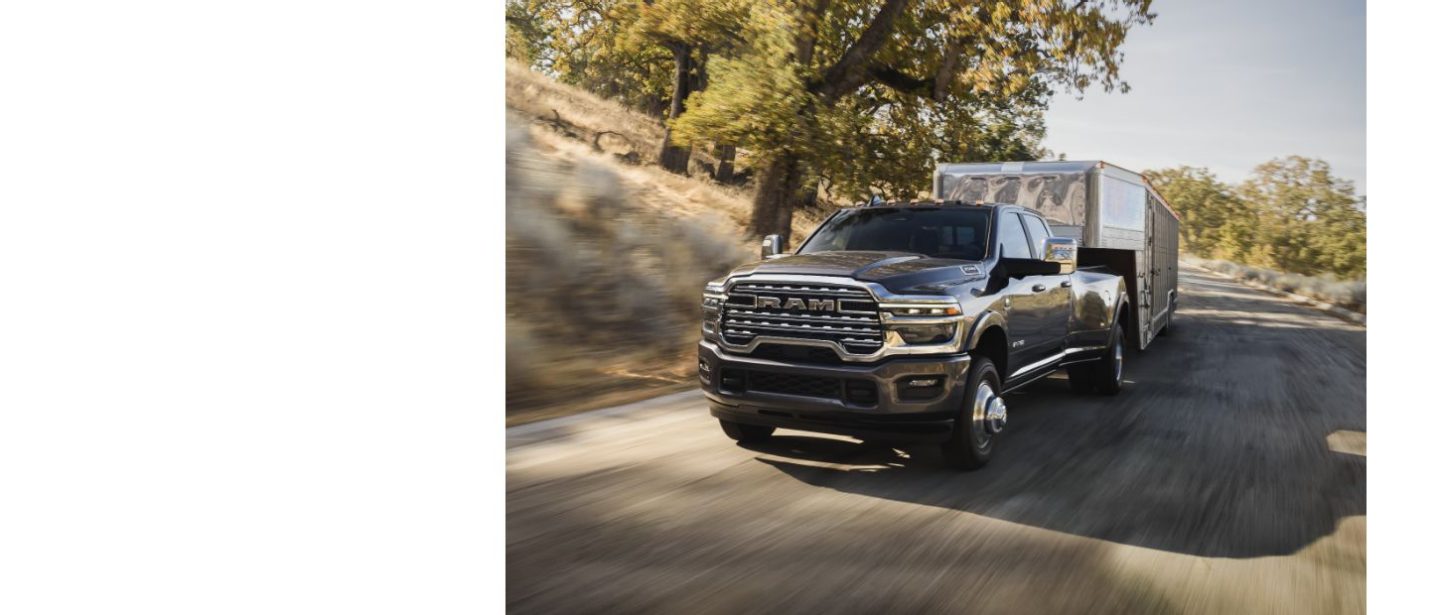 Una Ram 3500 Limited Longhorn 4x4 Crew Cab 2025 circulando por una carretera, acarreando un remolque de quinta rueda grande para ganado.