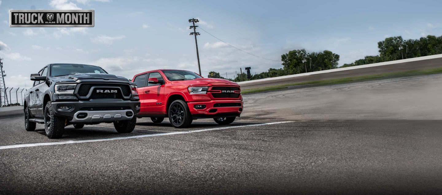 Un Ram 1500 Rebel 2022 negru și un Ram 1500 Laramie 2022 roșu la linia de start a unei piste de curse. Sigla Ram Truck Month.