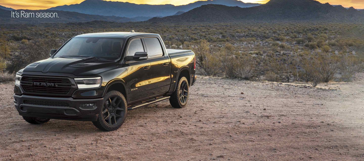 A black 2023 Ram 1500 Laramie 4x4 Crew Cab parked on a clearing in the desert at dusk. It's Ram season.