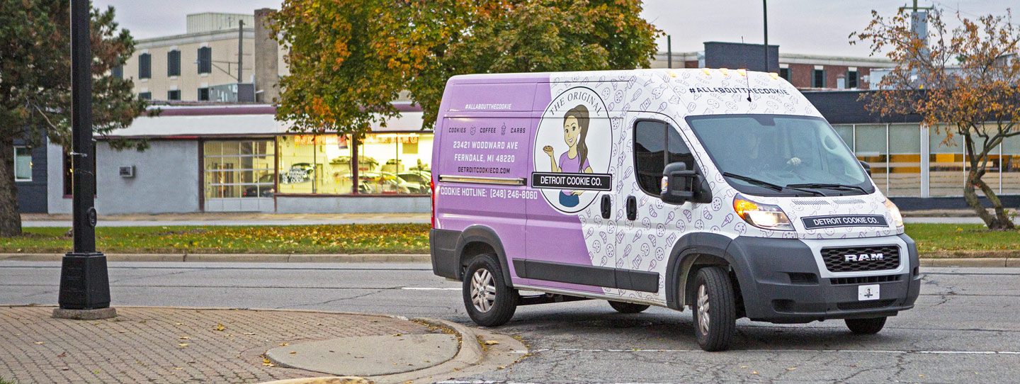 The Detroit Cookie Company Ram ProMaster van turning a corner on a city street.