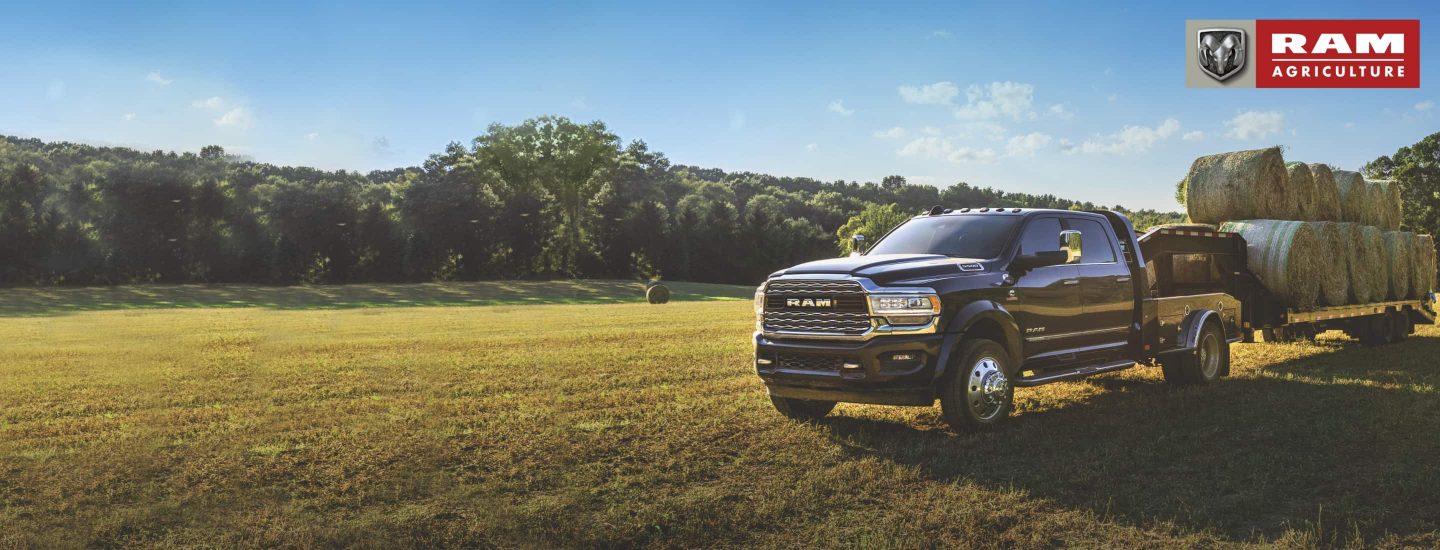 Ram Agriculture. The 2022 Ram 5500 Limited Chassis Cab towing a flatbed stacked with several hay bales.
