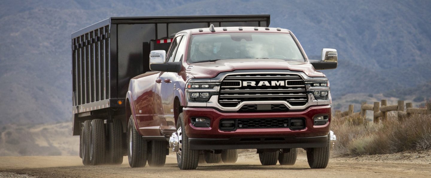 A red 2025 Ram 3500 Limited 4x4 Crew Cab towing an enclosed box.