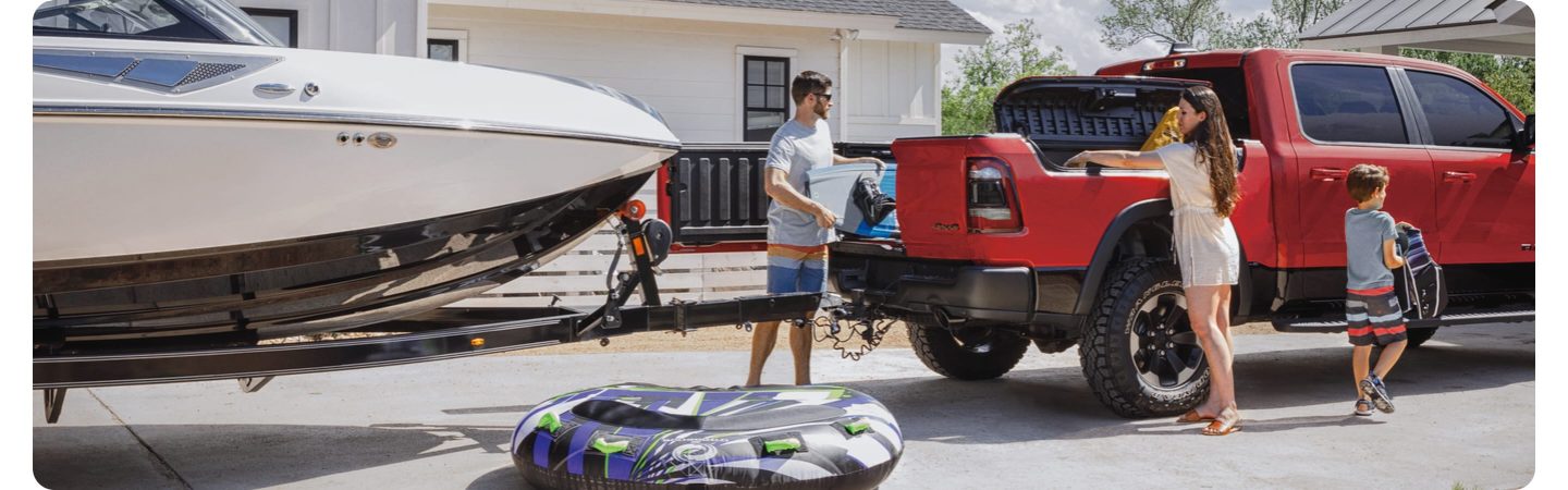 Una familia descargando una Ram 1500 2021 con una puerta abierta de su puerta trasera multifunción, sin obstáculos del bote que remolca la camioneta.