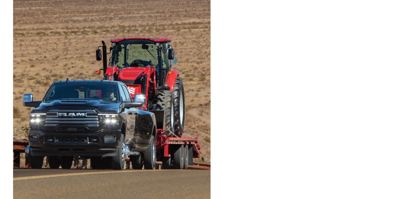 Una Ram 3500 Laramie Crew Cab 2026 negra circulando por una carretera, remolcando un vehículo de construcción.