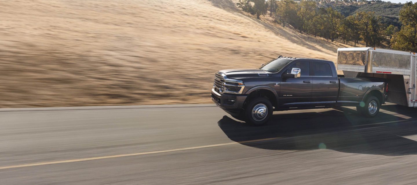 Una Ram 3500 Limited Longhorn 4x4 Crew Cab 2026 acarreando un remolque de quinta rueda grande para ganado y una Ram 2500 Rebel 4x4 Crew Cab 2026 estacionadas cerca entre sí. Ram Professional.