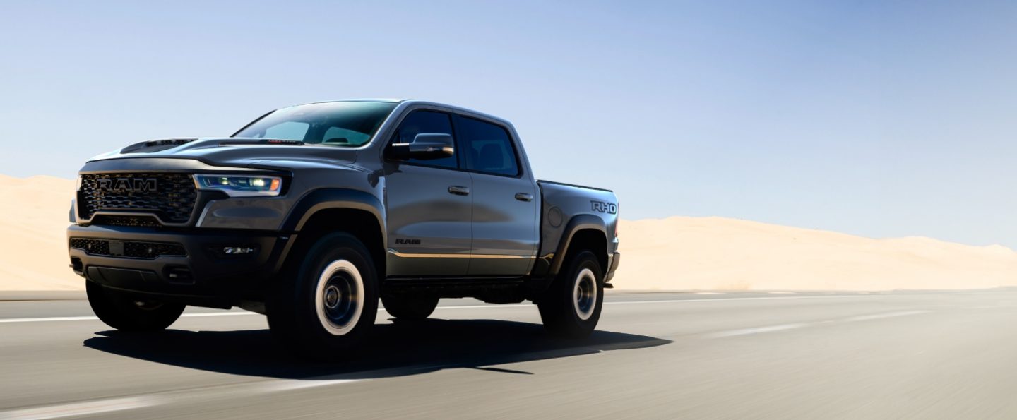 Una Ram 1500 RHO 4x4 Crew Cab 2027 gris andando por una carretera en el desierto.