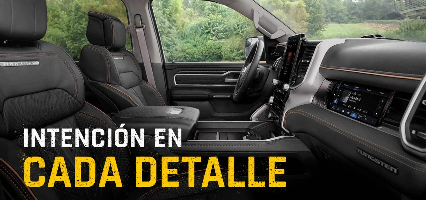 La primera fila de una Ram 1500 Tungsten 4x4 Crew Cab 2027 fotografiada desde el lado del pasajero, con asientos individuales de color gris oscuro y una pantalla táctil interactiva para el pasajero delantero. Intención en cada detalle.