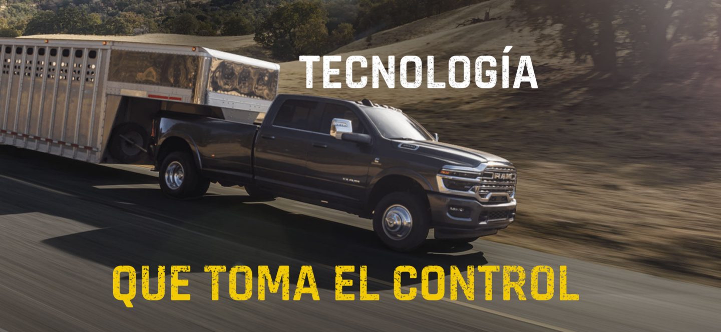 Una pick up Ram 3500 Heavy Duty Limited Longhorn 4x4 Crew Cab 2027 gris circulando por una autopista acarreando un remolque de quinta rueda grande para ganado. Tecnología al mando.