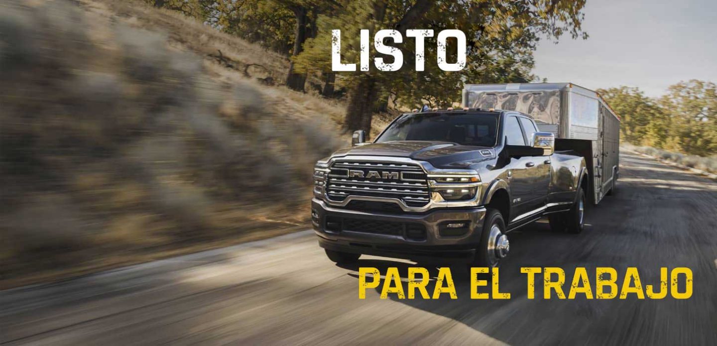 Una pick up Ram 3500 Heavy Duty Limited Longhorn 4x4 Crew Cab 2027 gris circulando por una autopista acarreando un remolque de quinta rueda grande para ganado. Lista para el trabajo.