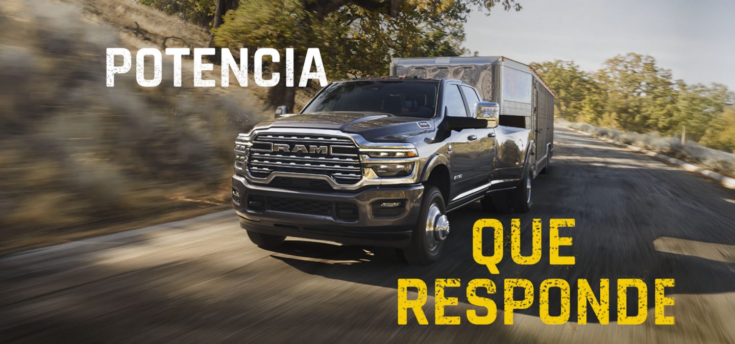 Una pick up Ram 3500 Heavy Duty Limited Longhorn 4x4 Crew Cab 2027 gris circulando por una autopista acarreando un remolque de quinta rueda grande para ganado. Potencia que supera cualquier desafío.