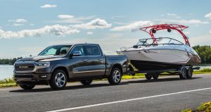 The Ram 1500 towing a motorboat on an open road.