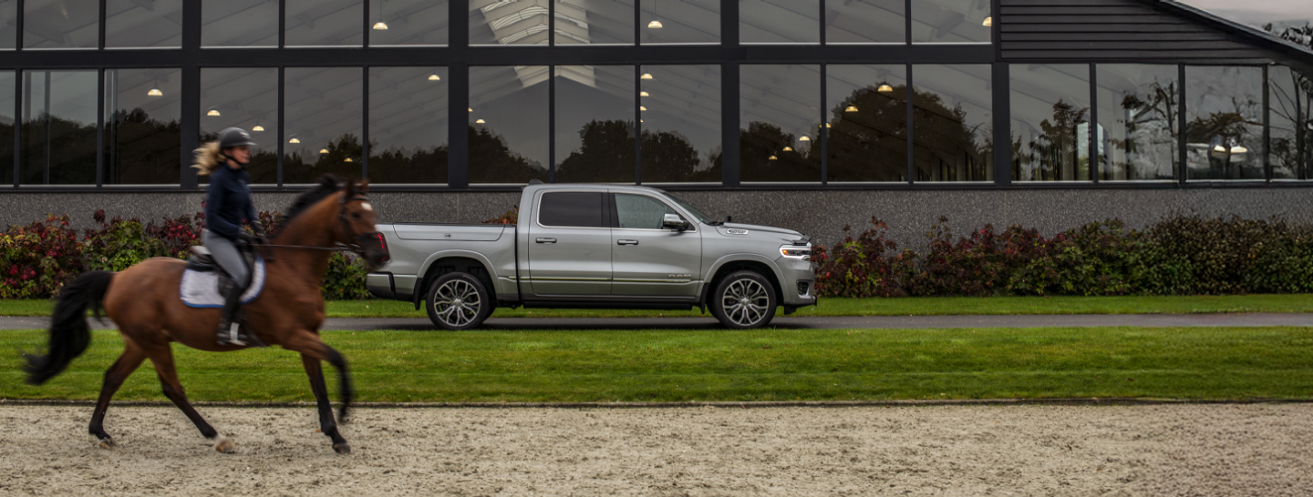 Vic Manson standing next to the hood of the 2020 Ram 2500 Laramie Crew Cab with a large stainless steel V-style plow attachment, and the North Shore Mountains in the background.