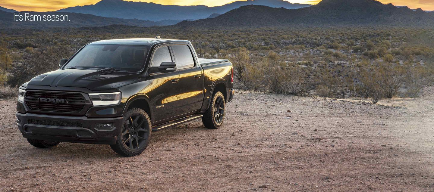 Черный 2023 Ram 1500 Laramie 4x4 Crew Cab припаркован на поляне в пустыне в сумерках. Это сезон Ram.