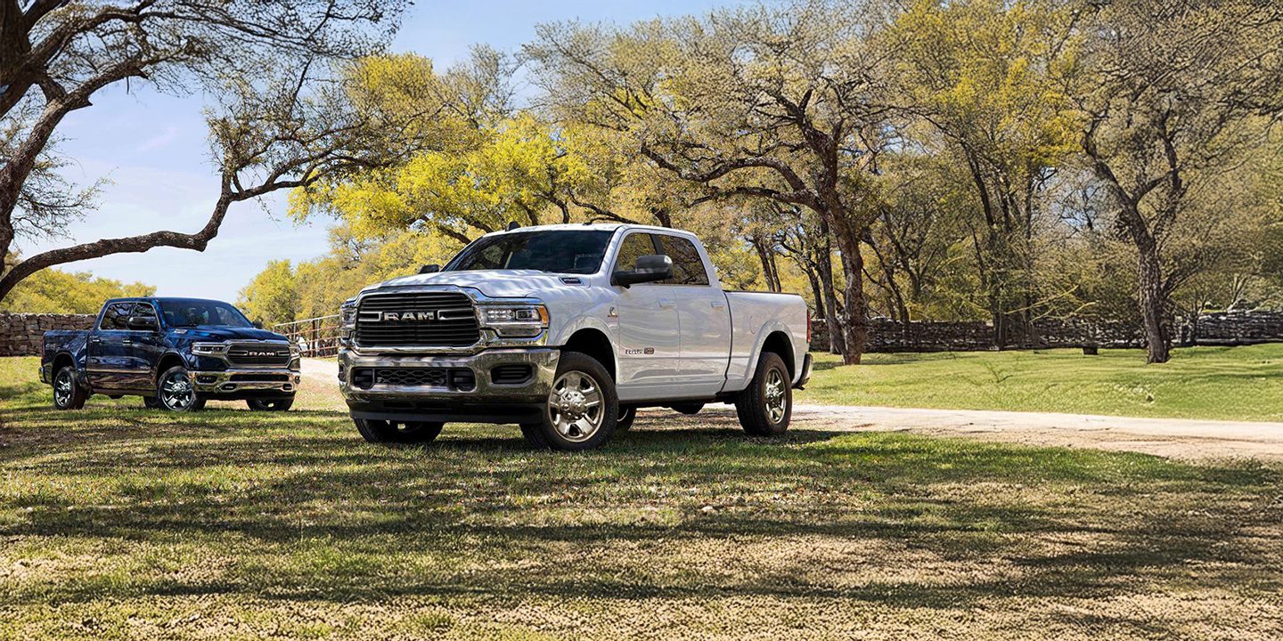 An angled profile of a red 2023 Ram 2500 Limited parked in a commercial garage with its headlamps on.