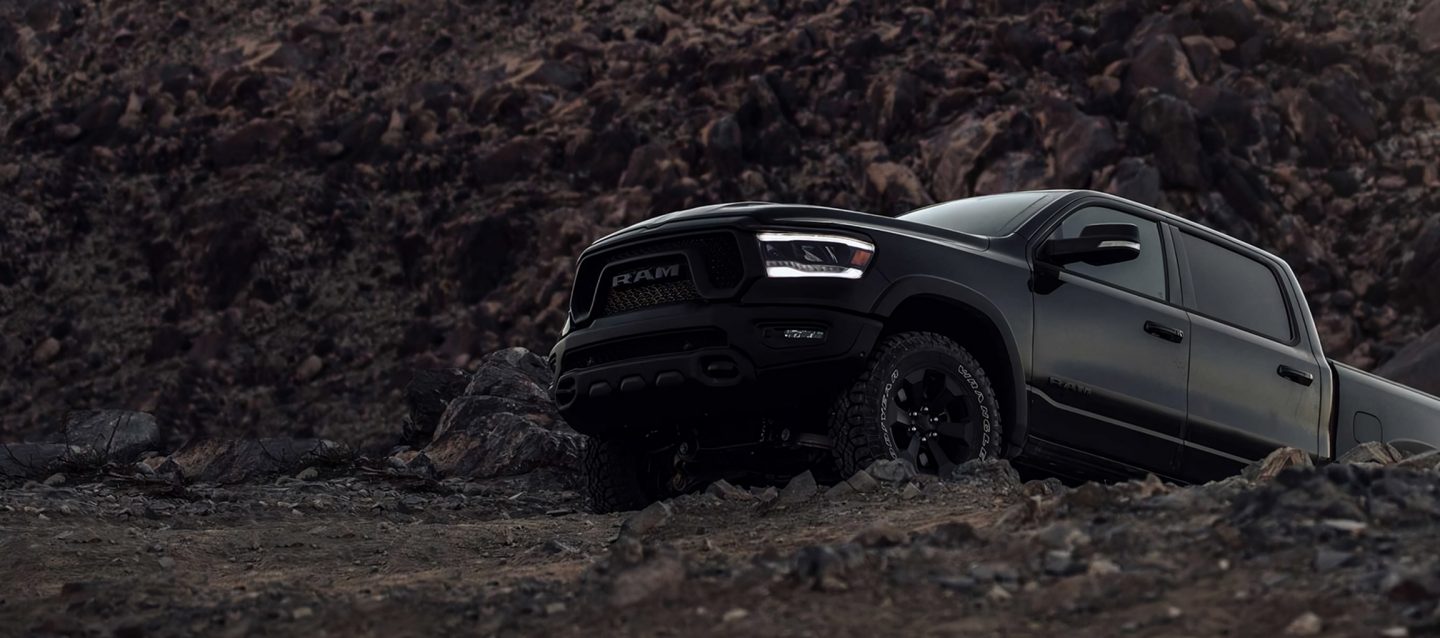 A black 2023 Ram 1500 Laramie 4x4 Crew Cab parked on a clearing in the desert at dusk. It's Ram season.